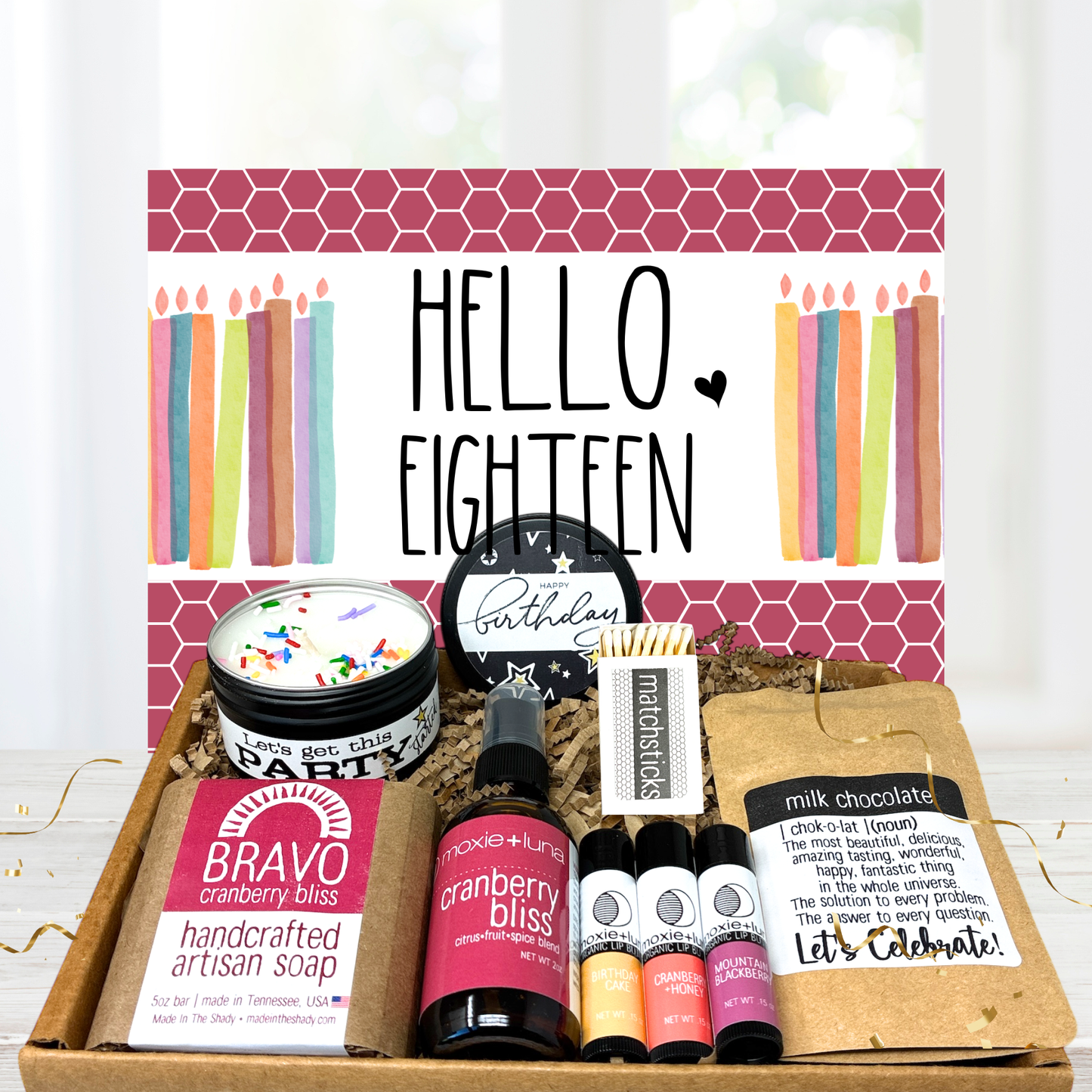 Gift set with 'Hello Eighteen' theme featuring candles, soap, and other items on a white background.